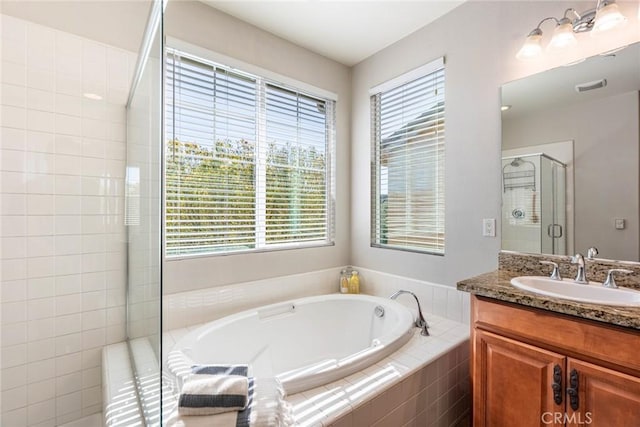 full bathroom with a bath, vanity, a shower stall, and visible vents