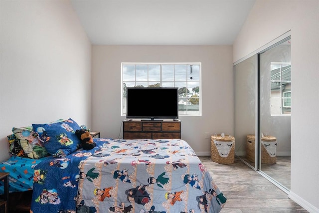 bedroom with baseboards, wood finished floors, and a closet