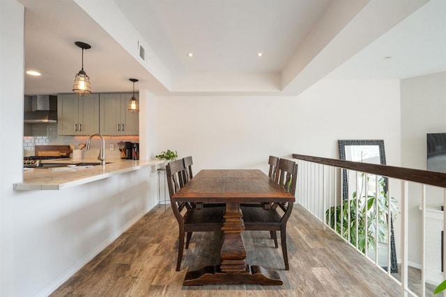 dining space featuring a tray ceiling, visible vents, baseboards, recessed lighting, and wood finished floors