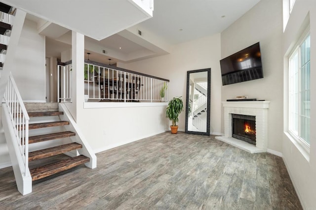 unfurnished living room with a fireplace, wood finished floors, baseboards, and stairs