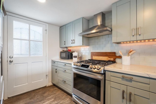 kitchen featuring dark wood-style floors, wall chimney range hood, black microwave, gas range, and gray cabinetry