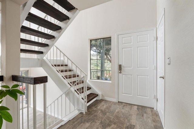 entrance foyer featuring baseboards, wood finished floors, and stairs