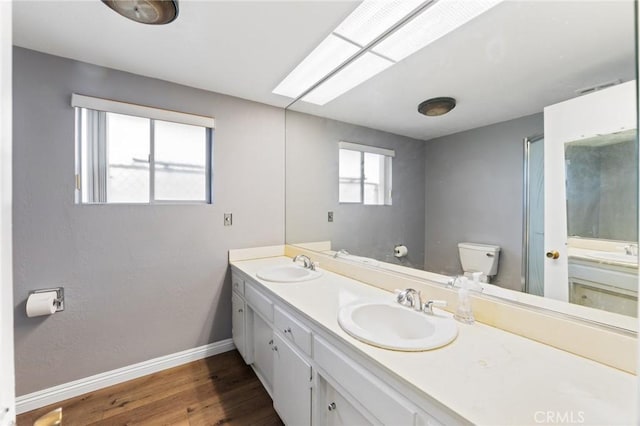 bathroom with baseboards, toilet, wood finished floors, and a sink