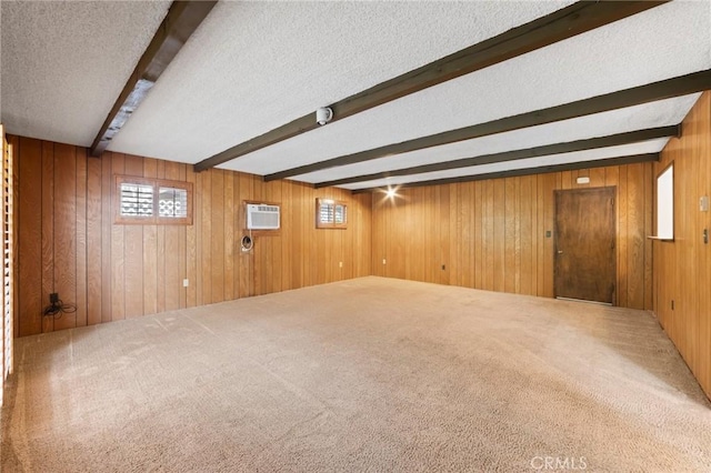 below grade area featuring wood walls, carpet flooring, a textured ceiling, and an AC wall unit
