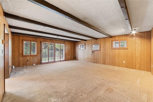 carpeted spare room with a wall mounted AC, wood walls, a textured ceiling, and beamed ceiling