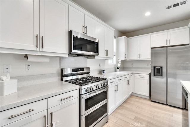 kitchen with light wood-type flooring, visible vents, recessed lighting, white cabinetry, and appliances with stainless steel finishes
