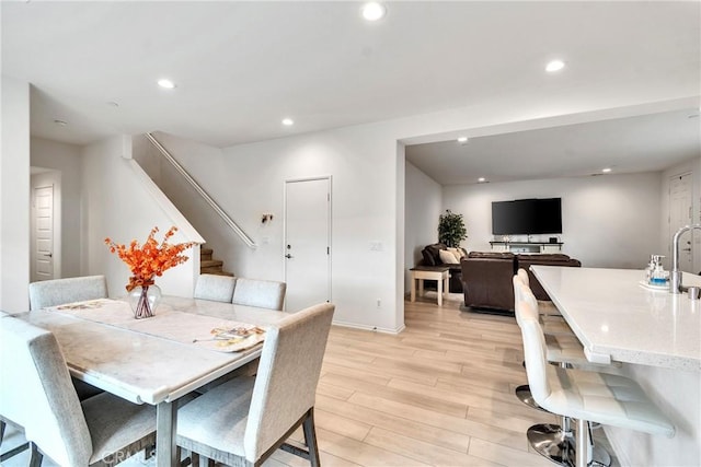 dining room with recessed lighting, baseboards, light wood-style floors, and stairs