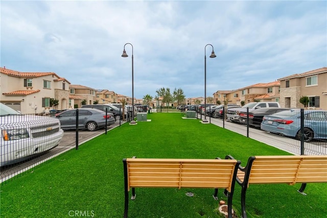 view of home's community featuring fence, a yard, and a residential view