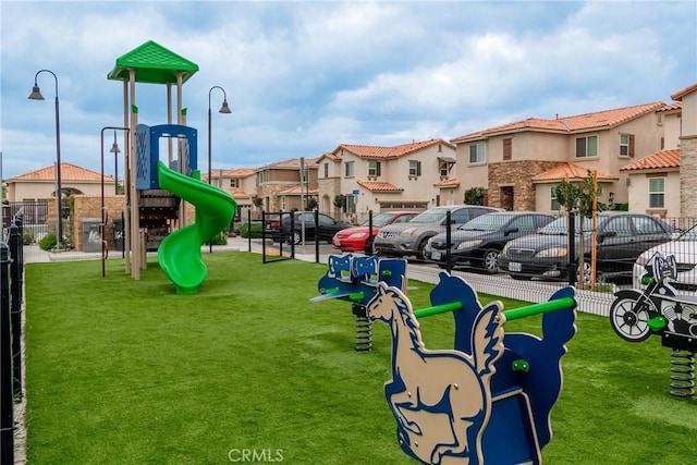 community play area featuring fence, a yard, and a residential view