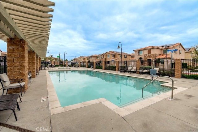 community pool with a patio area, fence, and a residential view