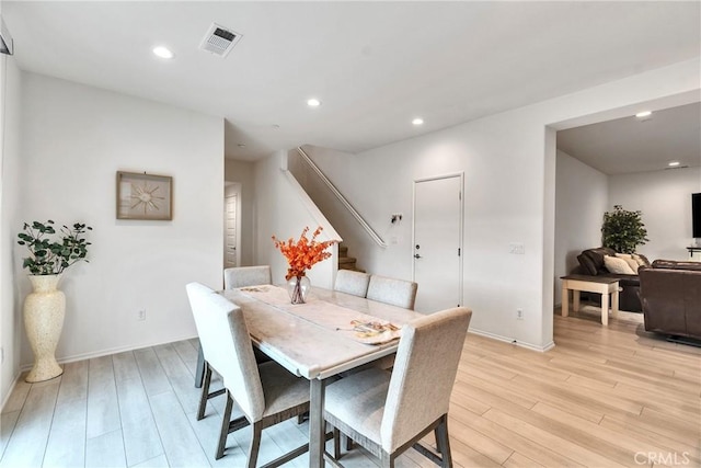 dining area with baseboards, stairs, visible vents, and light wood-type flooring