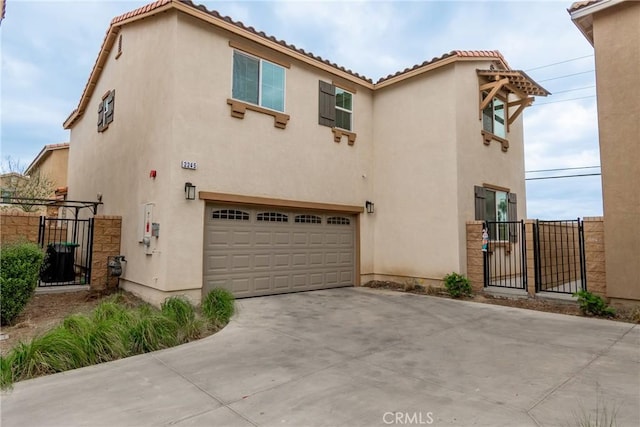 view of front of home featuring a gate, stucco siding, driveway, and a garage