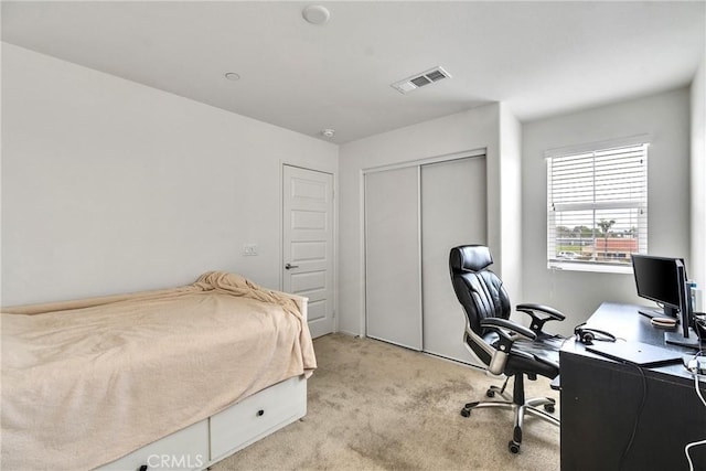bedroom with visible vents, a closet, and light colored carpet