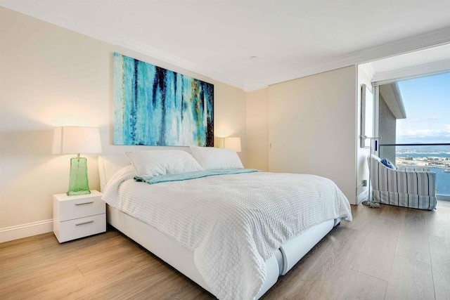 bedroom with baseboards, ornamental molding, and light wood finished floors