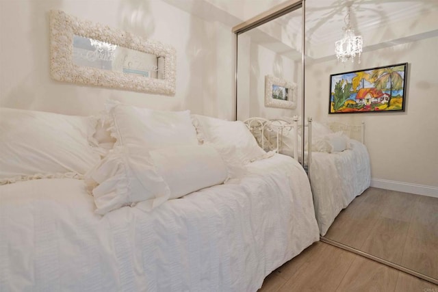 bedroom featuring baseboards, a chandelier, and wood finished floors