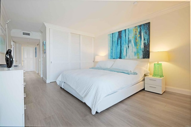 bedroom with light wood-type flooring, baseboards, visible vents, a closet, and ornamental molding