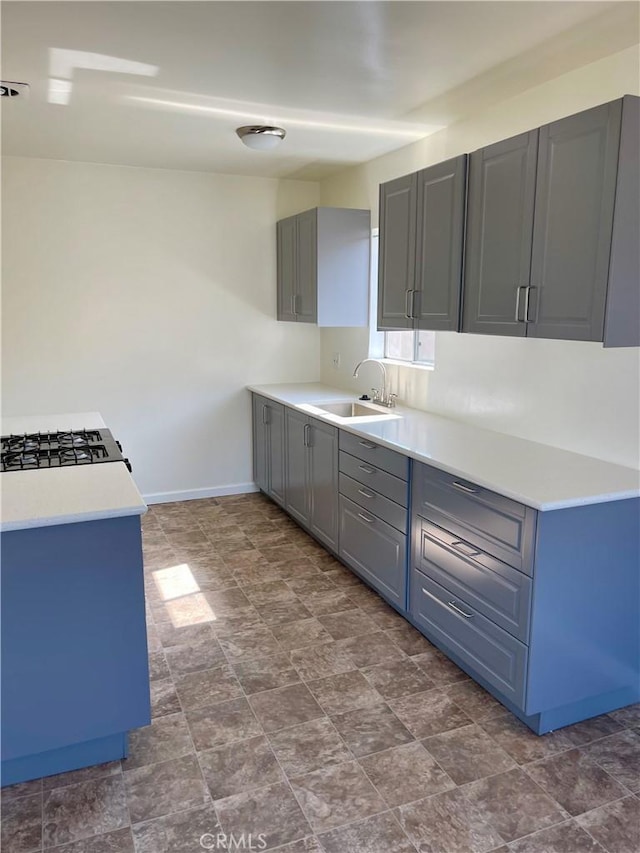 341 N Isabel St, Glendale, CA 91206 - kitchen with a sink, baseboards, gray cabinetry, stone finish floor, and light countertops