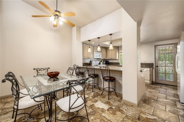 46375 Ryway Pl Unit 2, Palm Desert, CA 92260 - dining room with stone tile flooring, a ceiling fan, baseboards, and a high ceiling