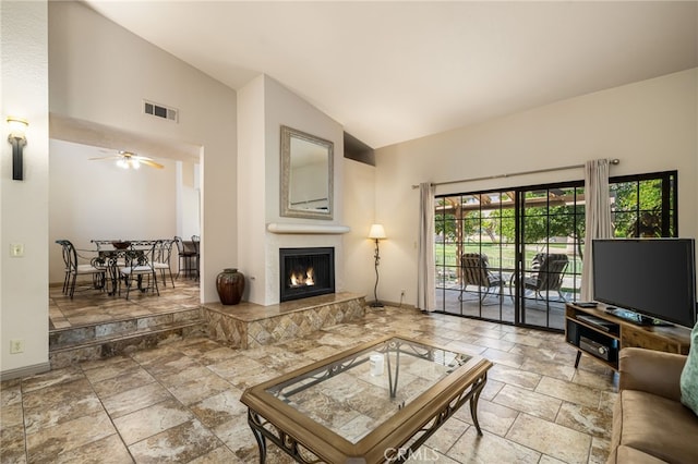 46375 Ryway Pl Unit 2, Palm Desert, CA 92260 - living room featuring vaulted ceiling, stone tile flooring, a warm lit fireplace, and ceiling fan