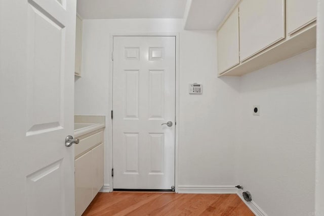 laundry area with cabinet space, light wood finished floors, electric dryer hookup, and baseboards
