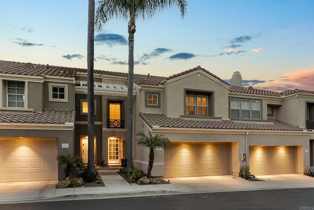 townhome / multi-family property with a tile roof, stucco siding, and driveway
