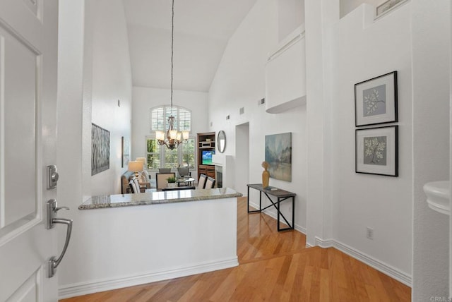 kitchen featuring high vaulted ceiling, a chandelier, light wood-style flooring, white cabinets, and hanging light fixtures