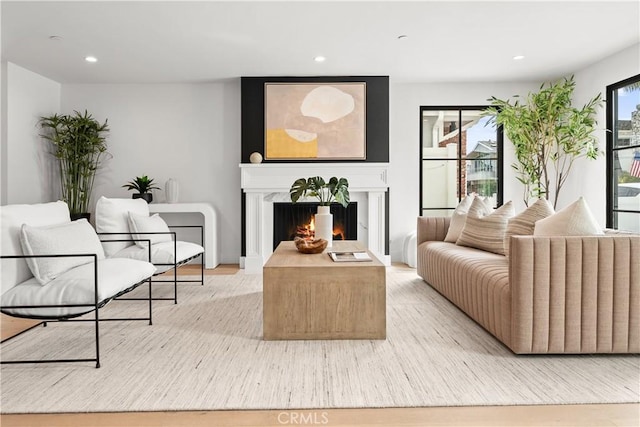 living room featuring light wood-type flooring, recessed lighting, and a premium fireplace