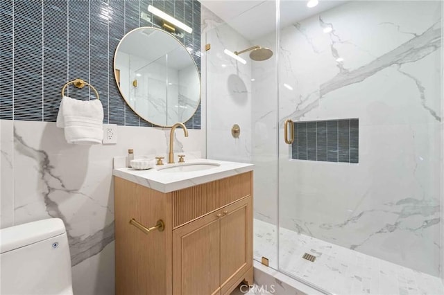 full bathroom featuring vanity, a marble finish shower, toilet, and tile walls
