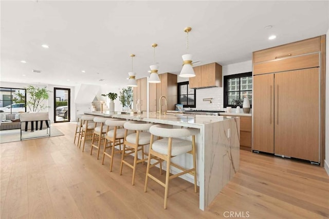 kitchen featuring a large island, a breakfast bar, light wood finished floors, and paneled fridge