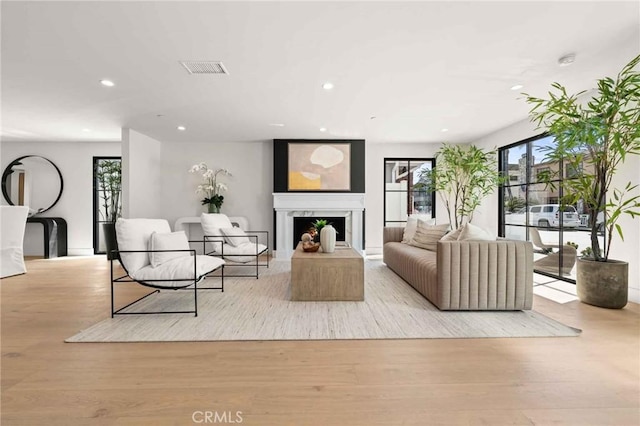 living room featuring a fireplace, recessed lighting, wood finished floors, and visible vents