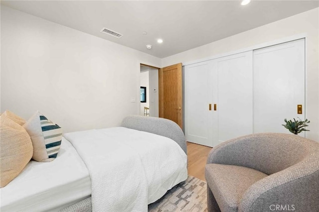 bedroom featuring visible vents, recessed lighting, light wood-style flooring, and a closet