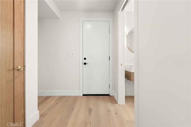 corridor featuring light wood-style floors and baseboards