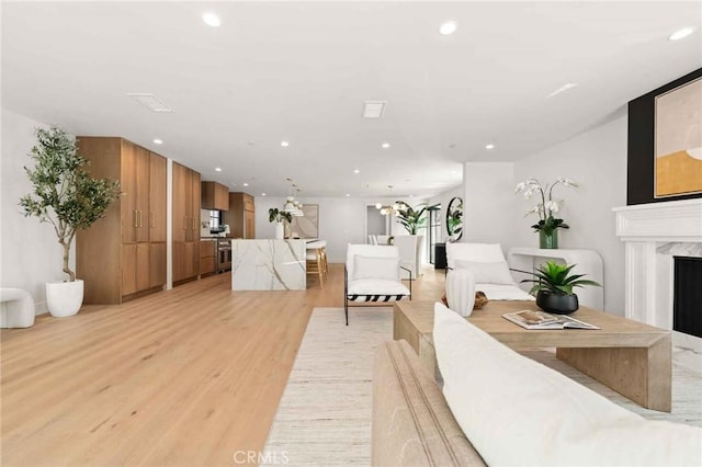 living area with recessed lighting, light wood-style flooring, and a fireplace