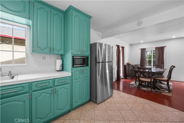 kitchen featuring built in microwave, light tile patterned floors, tasteful backsplash, light countertops, and freestanding refrigerator