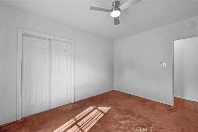 unfurnished bedroom with baseboards, a ceiling fan, carpet floors, and a closet