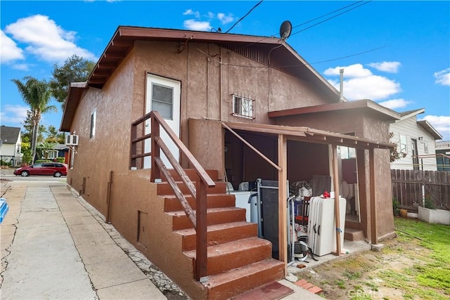 rear view of property with stucco siding and fence