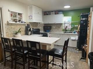 17838-17840 Los Alimos St, Granada Hills, CA 91344 - kitchen featuring a peninsula, a breakfast bar area, range, decorative backsplash, and light countertops