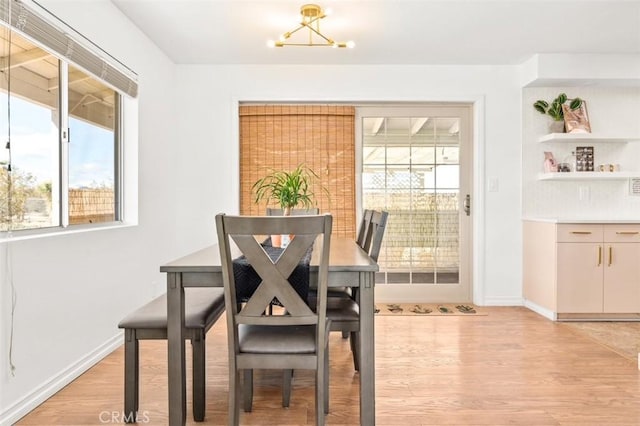 dining room with a notable chandelier, baseboards, and light wood-style floors