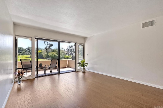 spare room with wood finished floors, baseboards, and plenty of natural light