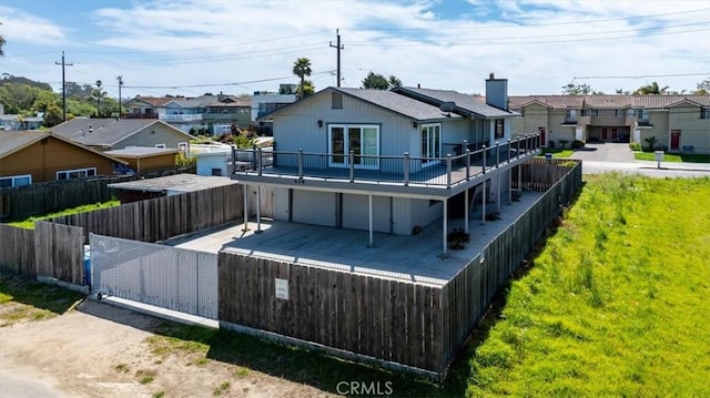 rear view of house with a fenced backyard, a residential view, a deck, and a lawn