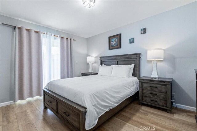 bedroom with baseboards and light wood finished floors