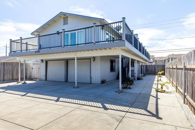 back of house with board and batten siding, an attached garage, a fenced backyard, and concrete driveway