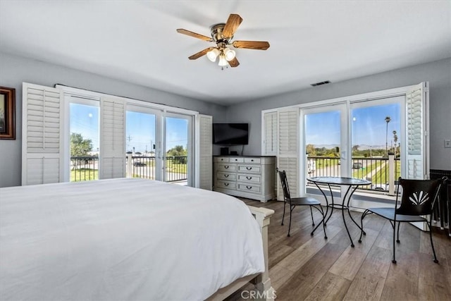 bedroom with wood finished floors, access to exterior, a ceiling fan, and visible vents