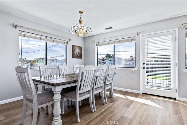 dining area with baseboards, visible vents, an inviting chandelier, and light wood-style floors