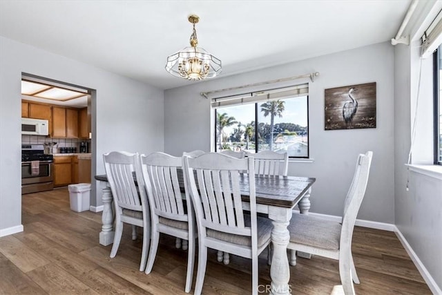 dining room featuring baseboards, an inviting chandelier, and light wood-style floors