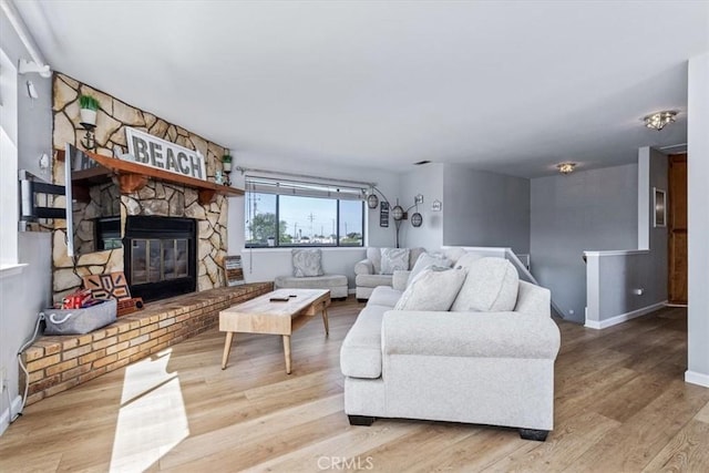 living area with a fireplace, wood finished floors, and baseboards