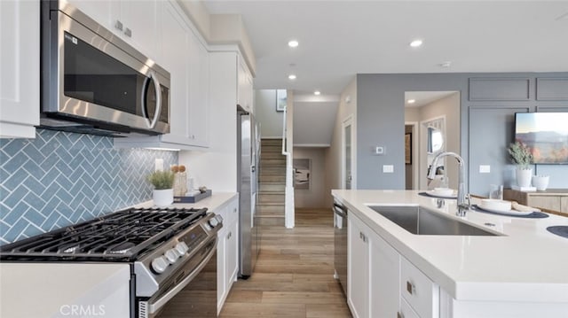 302 Fawn St, Rancho Mission Viejo, CA 92694 - kitchen featuring tasteful backsplash, a sink, an island with sink, stainless steel appliances, and light wood-style flooring
