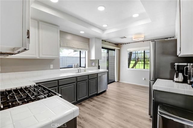 28 Dearborn Cir, Redlands, CA 92374 - kitchen with tile counters, appliances with stainless steel finishes, a tray ceiling, gray cabinetry, and white cabinets