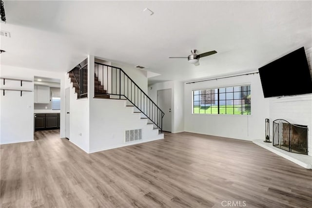 28 Dearborn Cir, Redlands, CA 92374 - unfurnished living room with a fireplace with raised hearth, ceiling fan, stairs, and light wood-style floors
