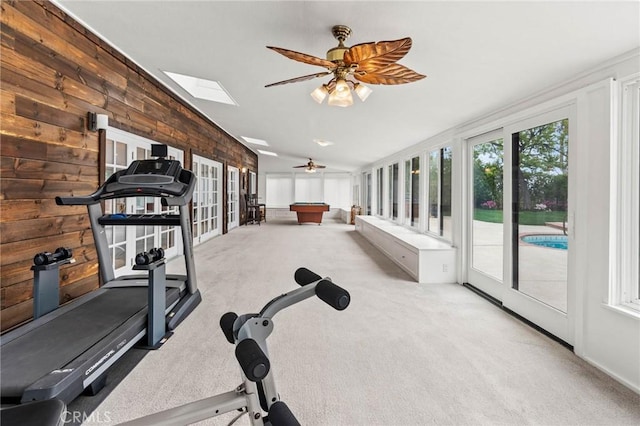 exercise area featuring wood walls, billiards, lofted ceiling with skylight, carpet flooring, and ceiling fan